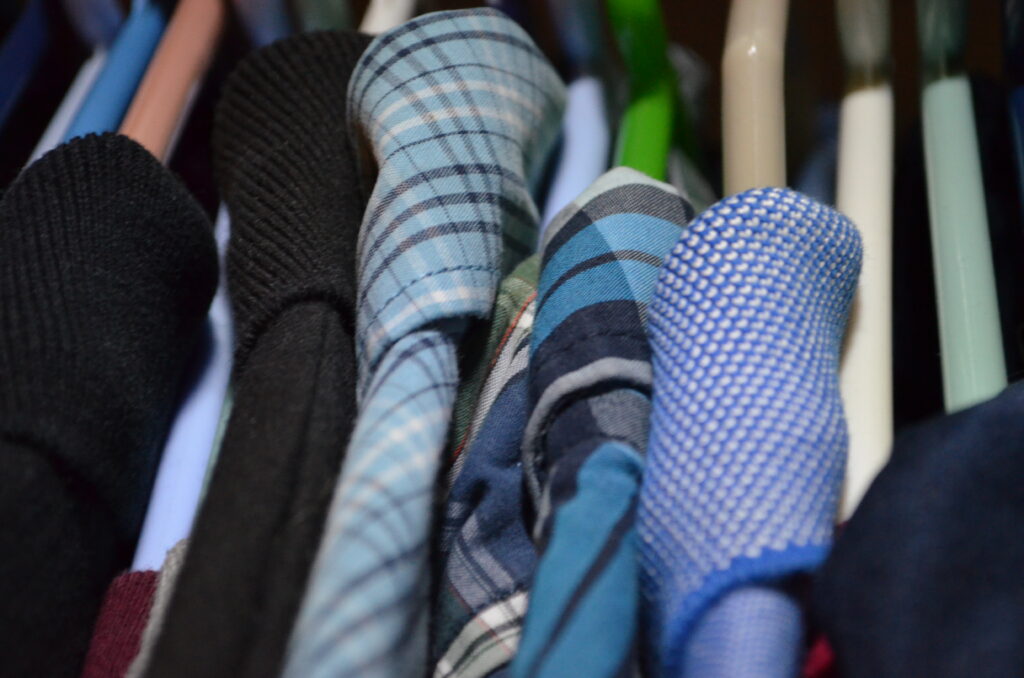 Alt Text: A variety of shirts hang in a closet. Most are blue, even more have collars. With summer vacation ending soon, these will once again be in use.